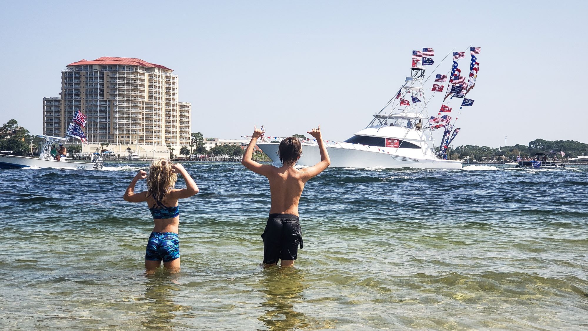 kids in the water during spring time in fort walton beach with boats and a building in the background