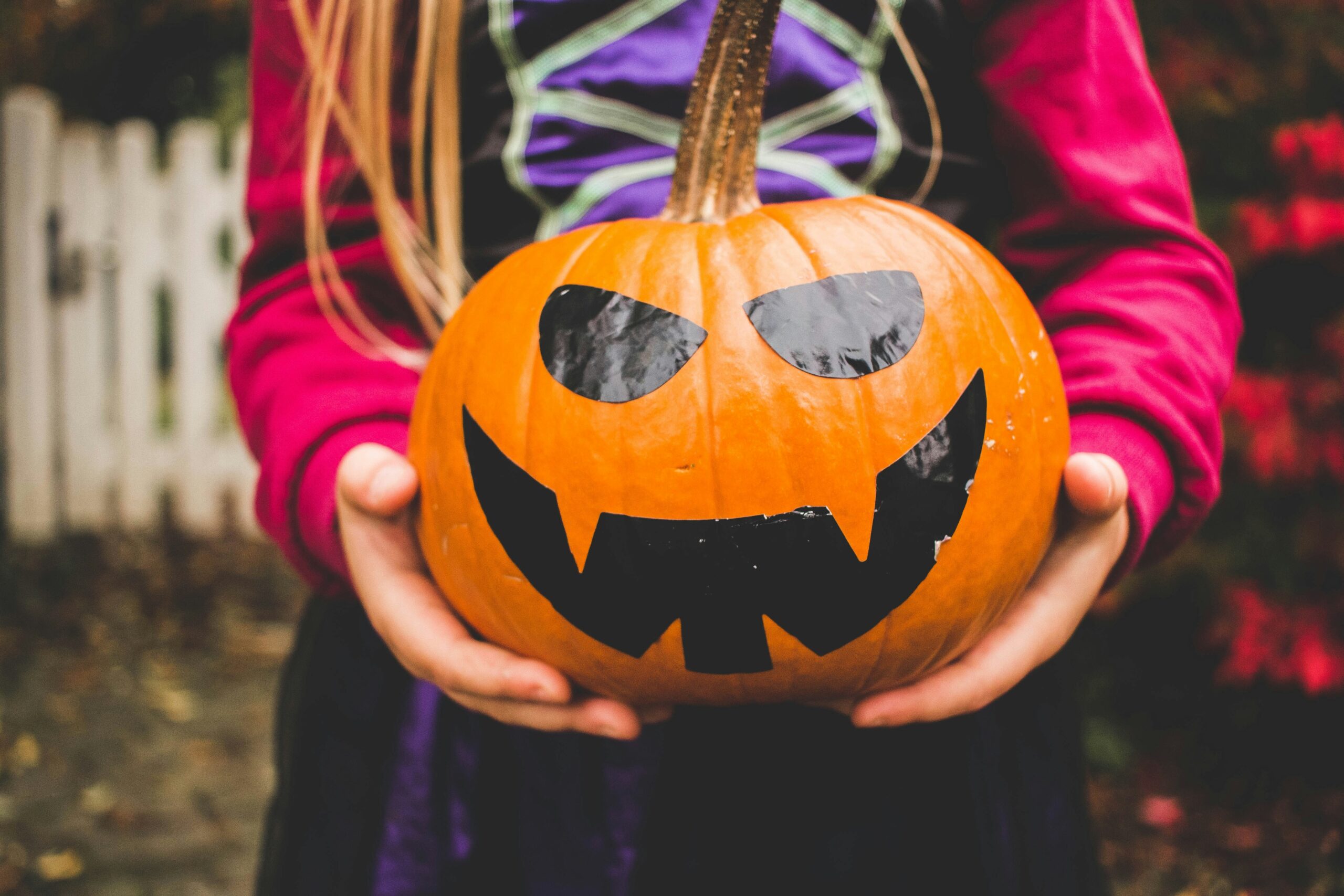 a person holding a pumpkin that is painted with a face for halloween