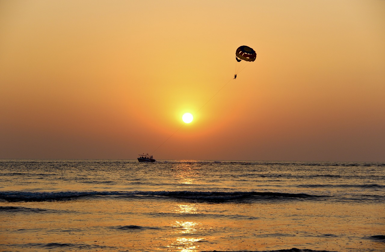 sunset on the beach with a parasail in the background