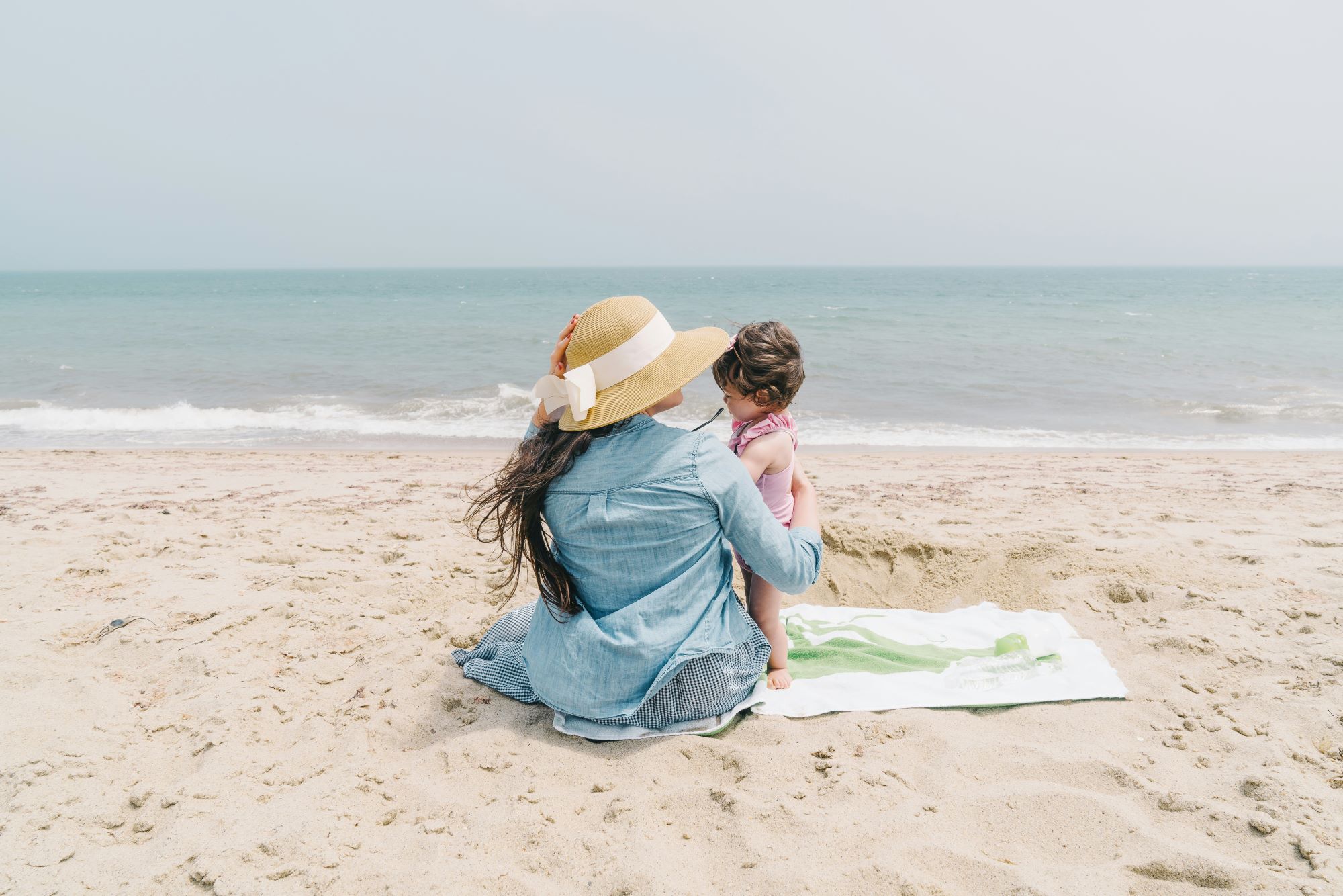 a woman in a blue outfit and a hat with a child on the beach