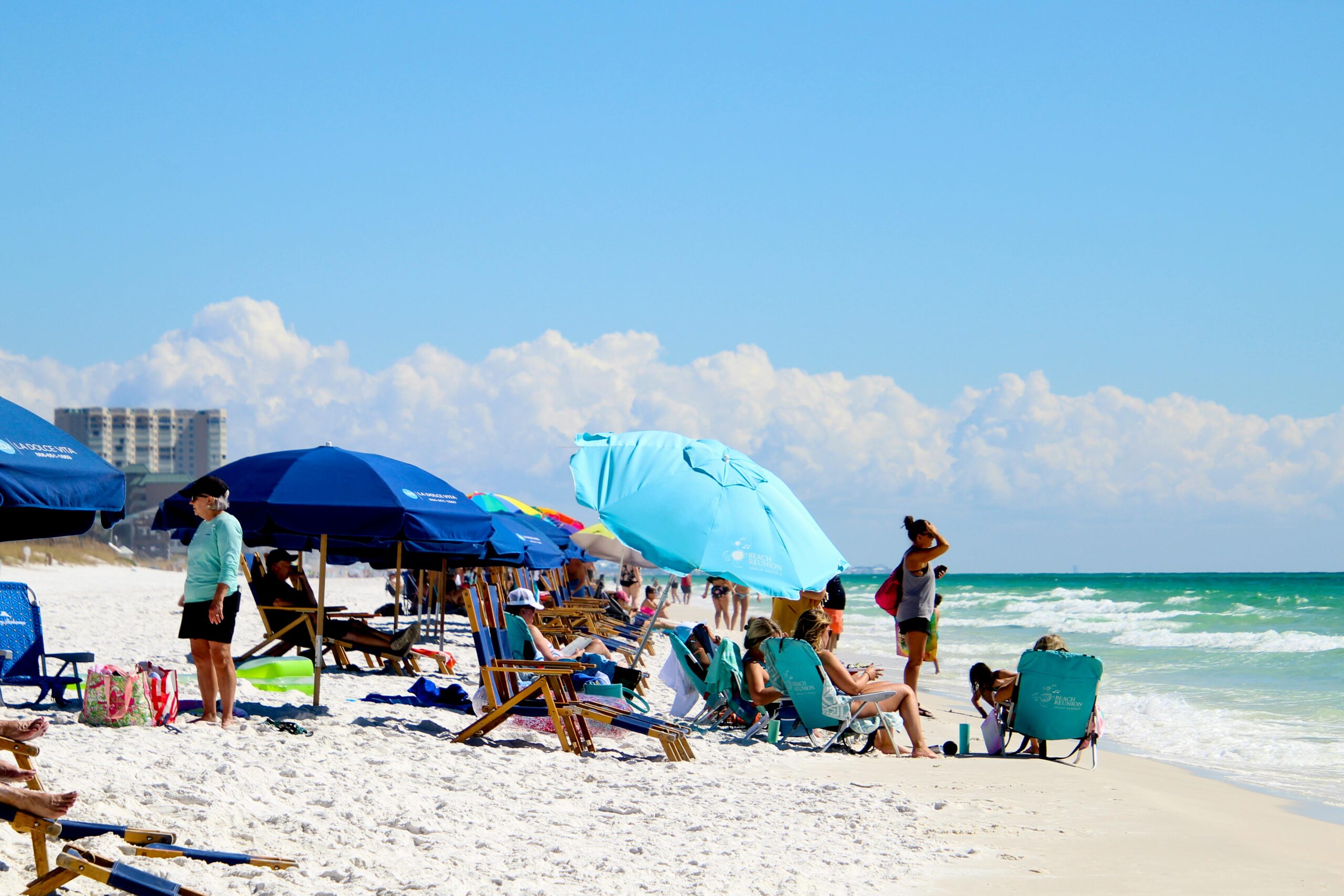 a beach with people and chairs and umbrellas