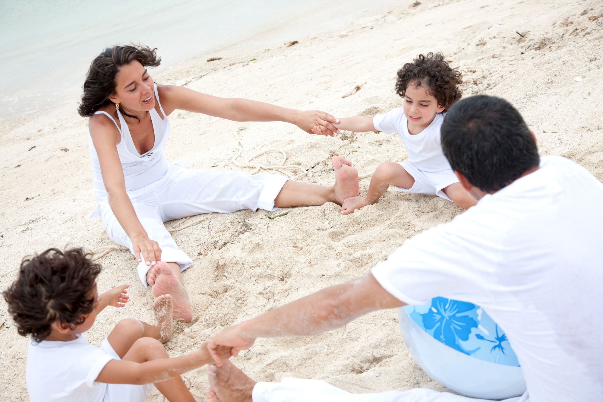 family and at the beach sitting on the sand and holding hands to make a circle